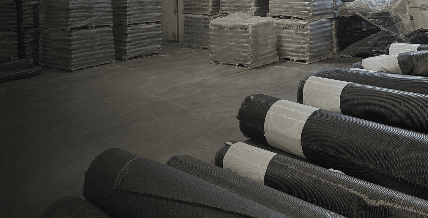 Rolls of artificial grass and palletized stock inside the AGD warehouse